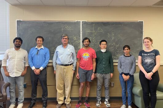 7 people stand before a blackboard